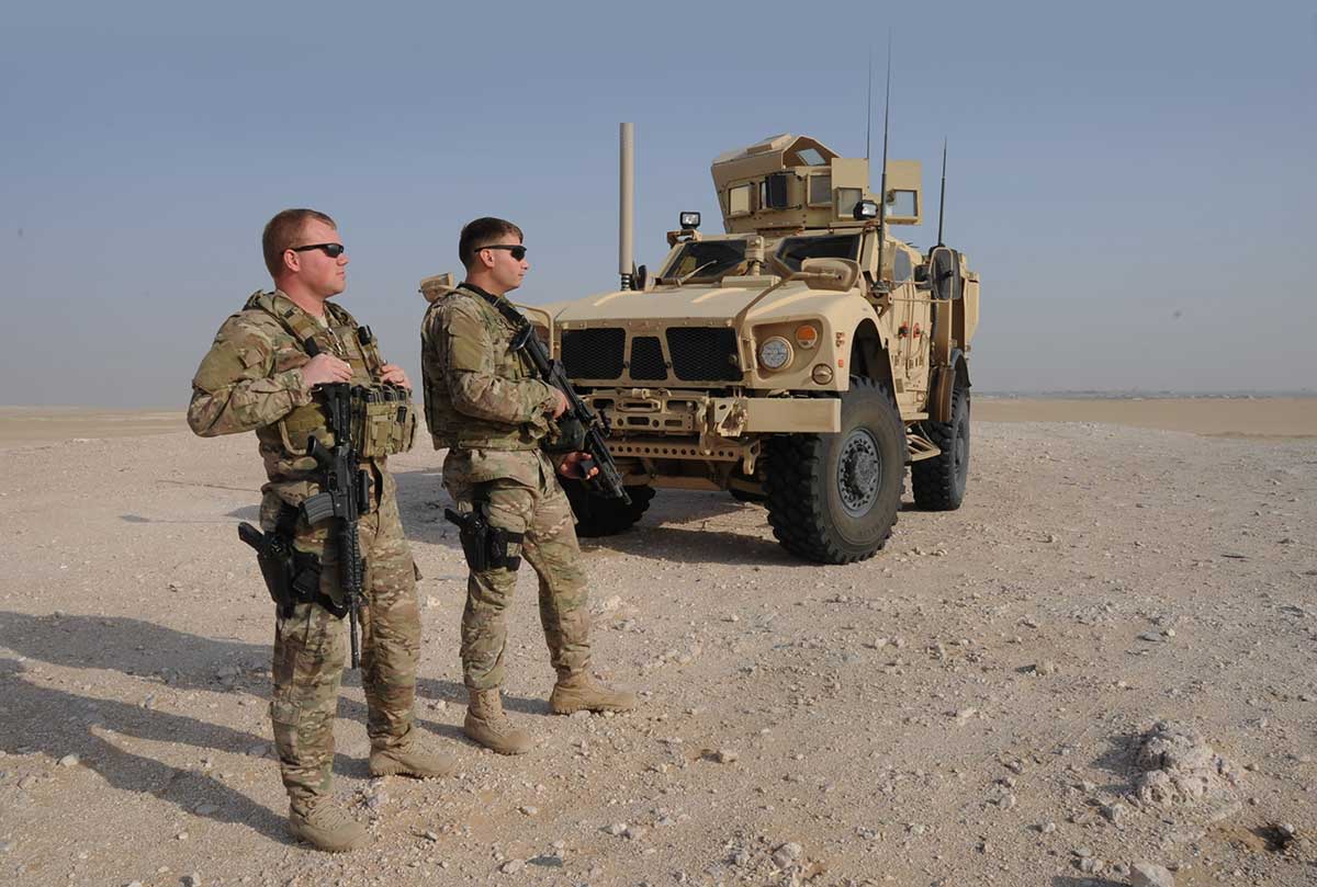 Service member in front of a vehicle.