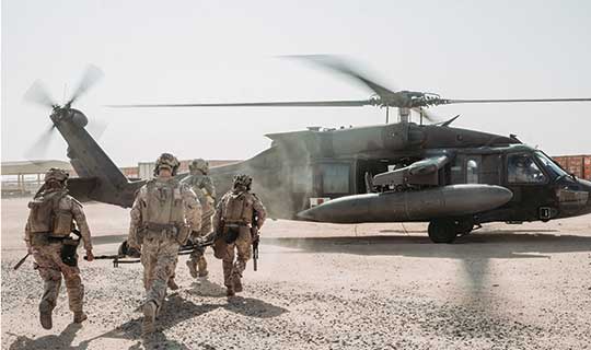 Service members walking to a helicopter.