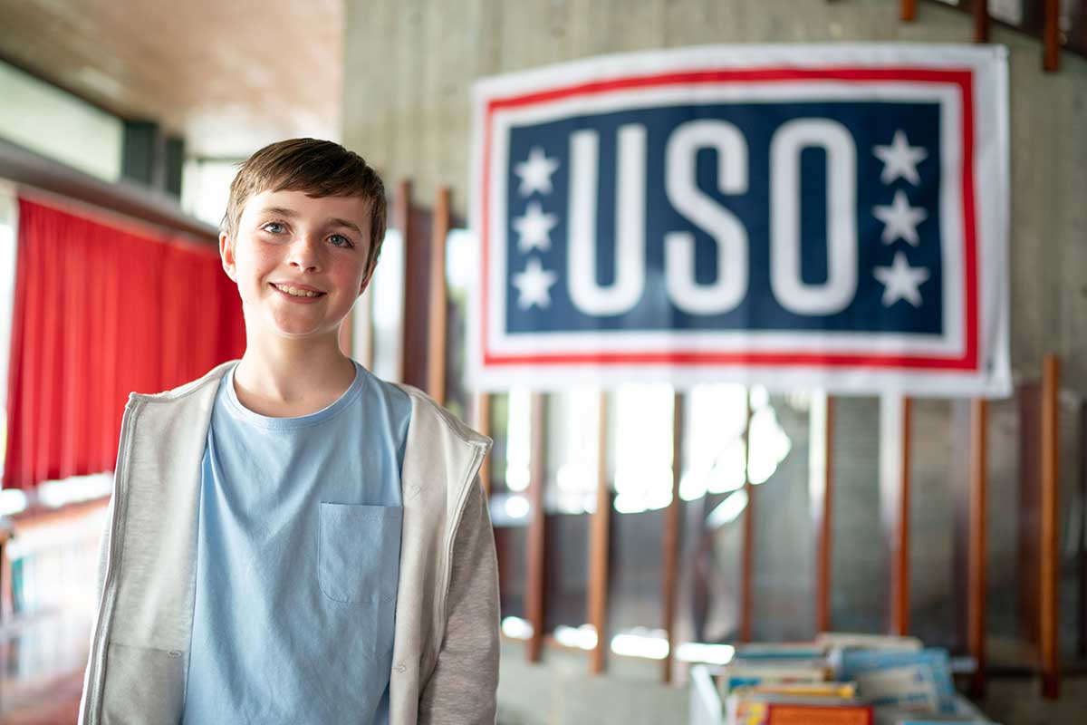 Liam smiling in front of a USO sign