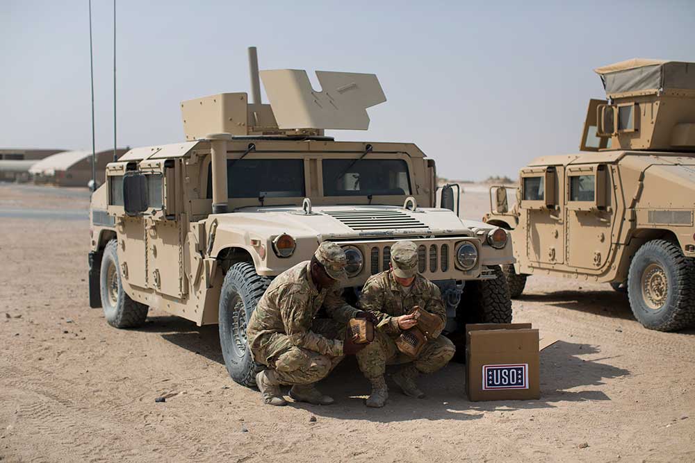 Service members taking supplies out of a USO box