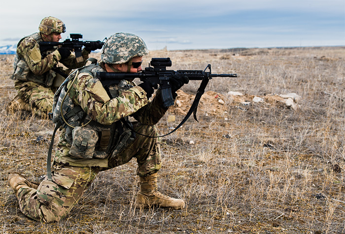 Service members aiming their guns in a field