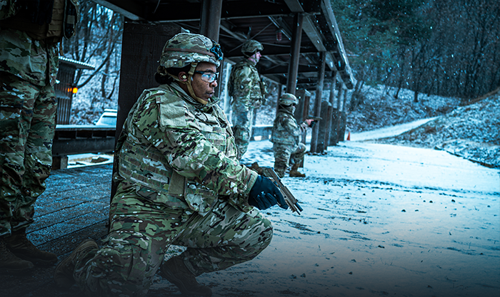 Service member aiming their gun in the snow