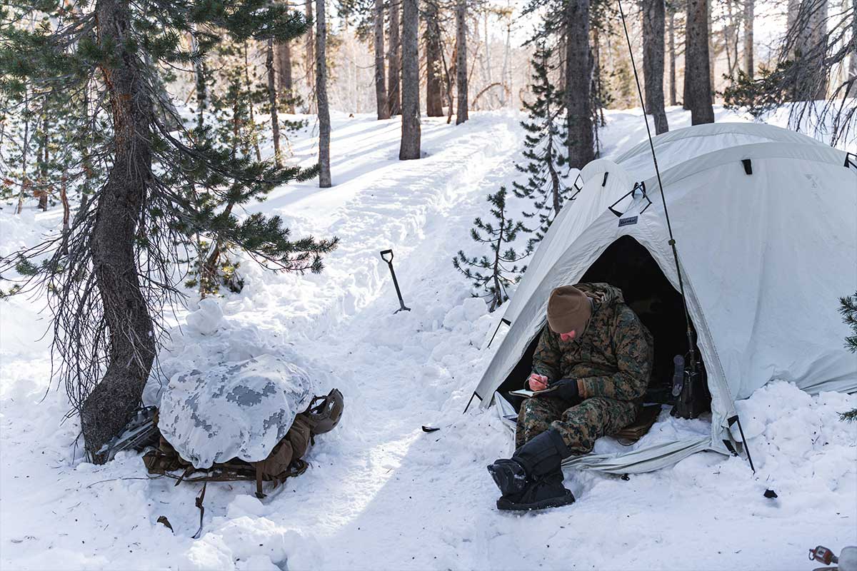 Service member camped in a tent in the snow